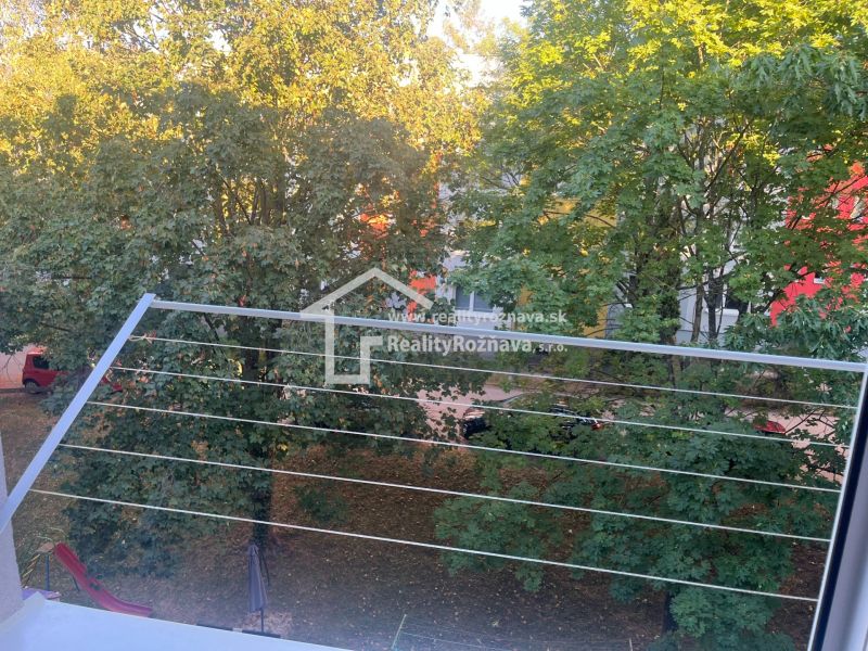 View from the balcony of a 2-room apartment in Rožňava to a green park with cars.