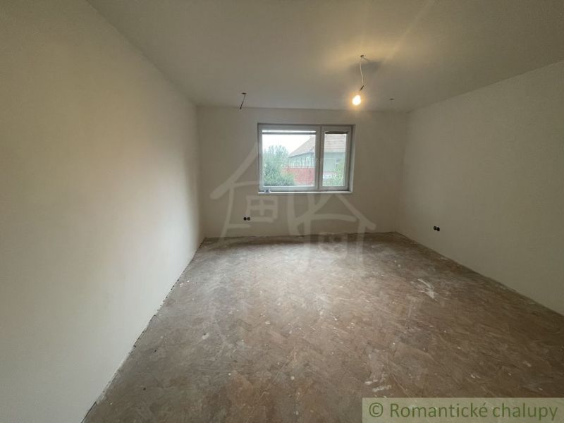 An empty room in a family house with a window and a wooden decor floor.