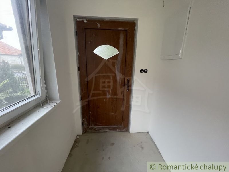 Entrance hallway with wooden doors in a family house, simple walls and a window.