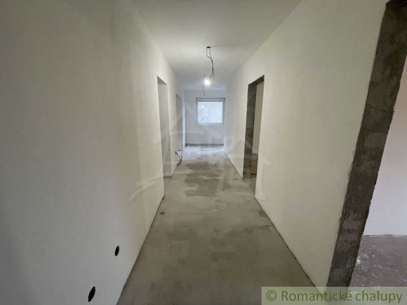 A hallway in a family house with smooth walls and a concrete floor.