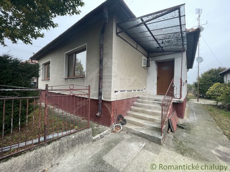 A family house in Šurany with a covered veranda, garden, and rustic fence.