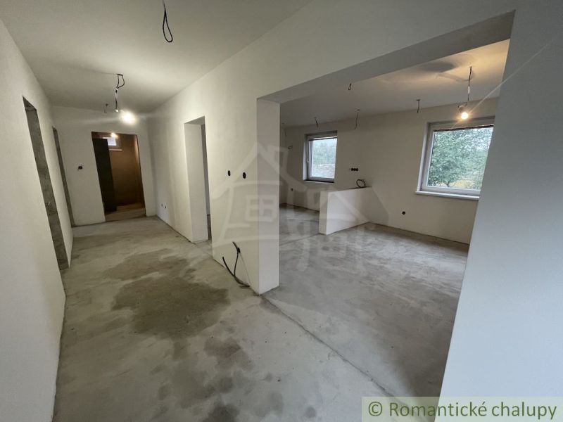 Interior of a family house with a concrete floor, white walls, and a view of the garden.