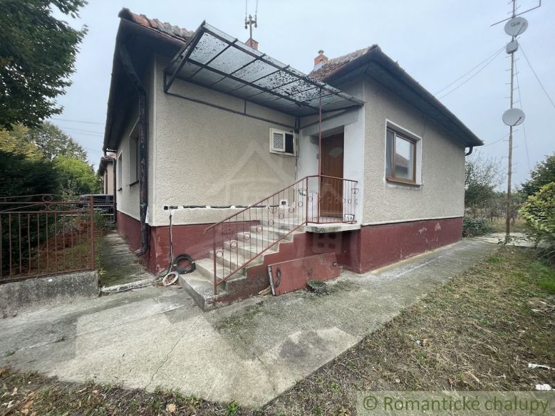 A family house in Šurany with plaster, metal railing, and a metal roof.