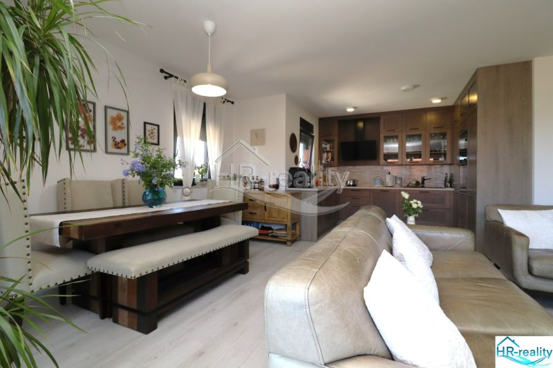 Recreational apartment with a kitchen, dining table, and sofa, floor with wooden decor.