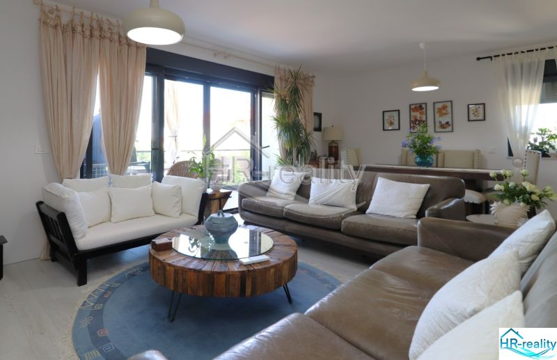 The holiday apartment offers a bright living room with comfortable sofas and wooden decor.