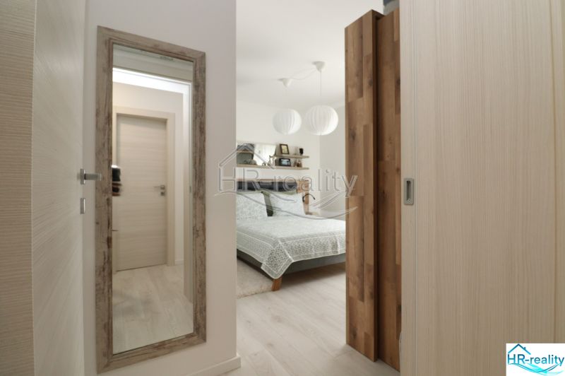 Bedroom in a vacation apartment with a mirror and a bed, floor with wood decor.