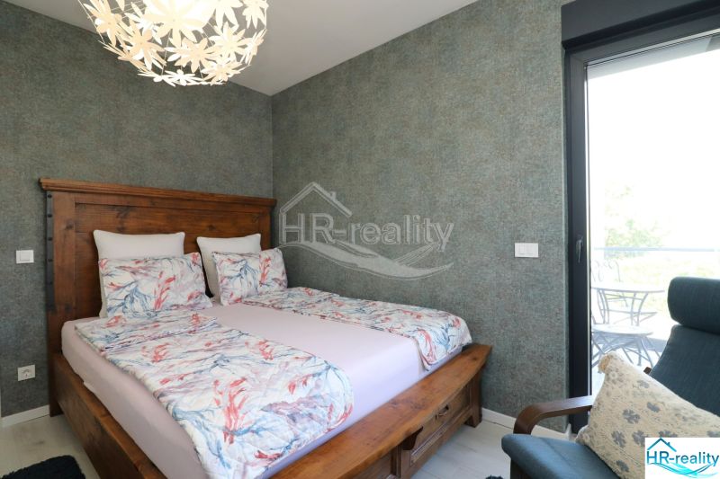 Double bed in a Holiday Apartment, with patterned linen and ceiling light.