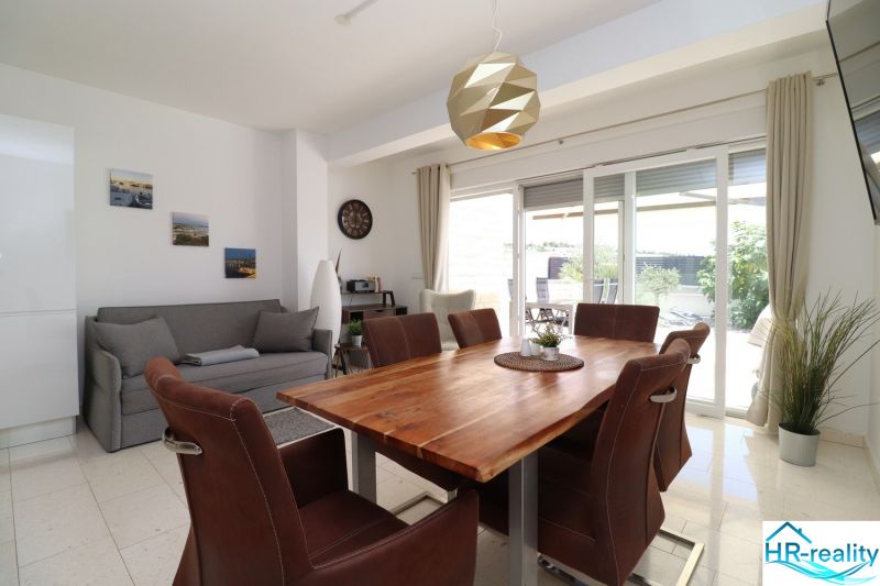 A recreational apartment with a dining table and a spacious living area with large windows.