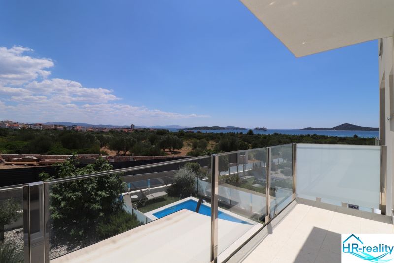 View from the holiday apartment in Tribunj of greenery, pool, and sea.