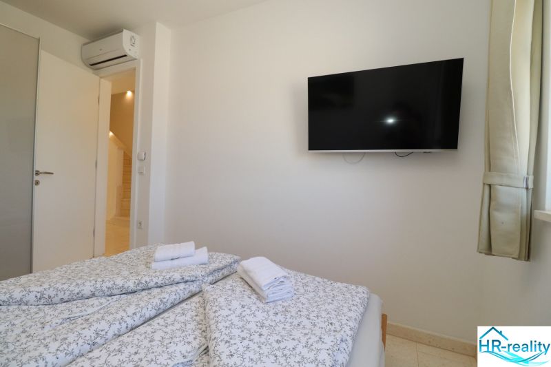Recreational apartment with air conditioning, TV, and a bed with floral bedding.