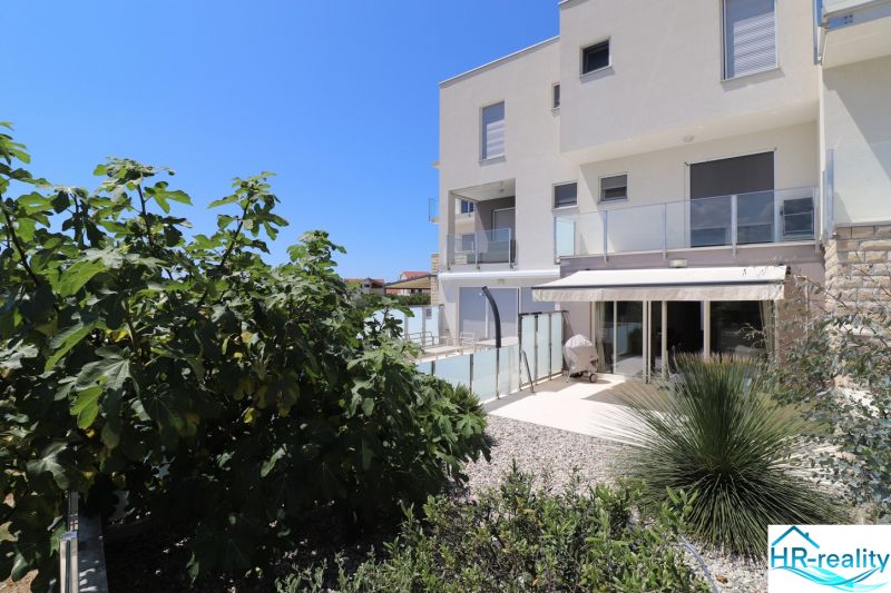 A holiday apartment in Tribunj with a terrace and a green garden under the blue sky.
