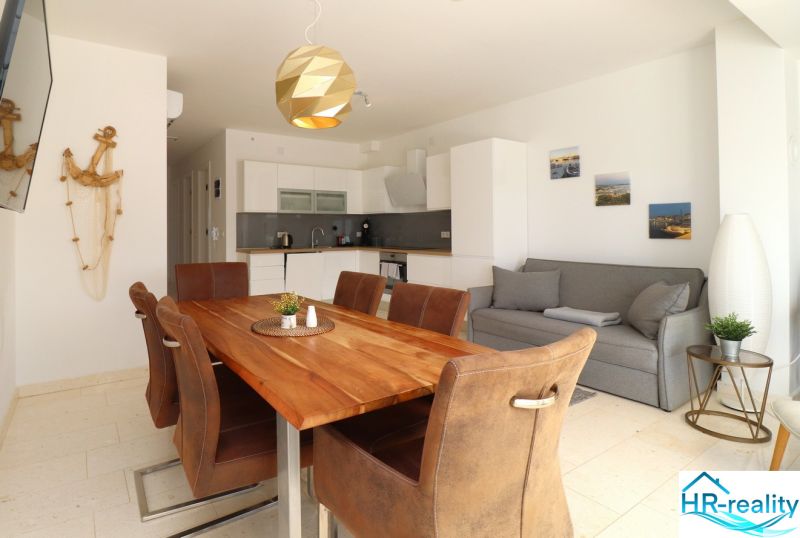 Recreational apartment with wood-patterned flooring, kitchen, and dining table with chairs.