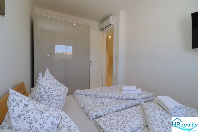 Bedroom in a holiday apartment with a bed, built-in wardrobe, and air conditioning.