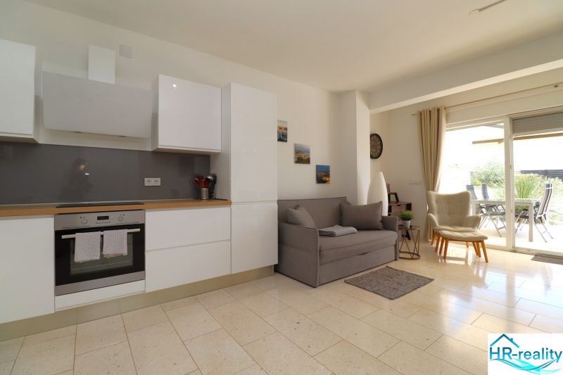 Bright interior of a holiday apartment with a kitchen, sofa, and outdoor terrace.