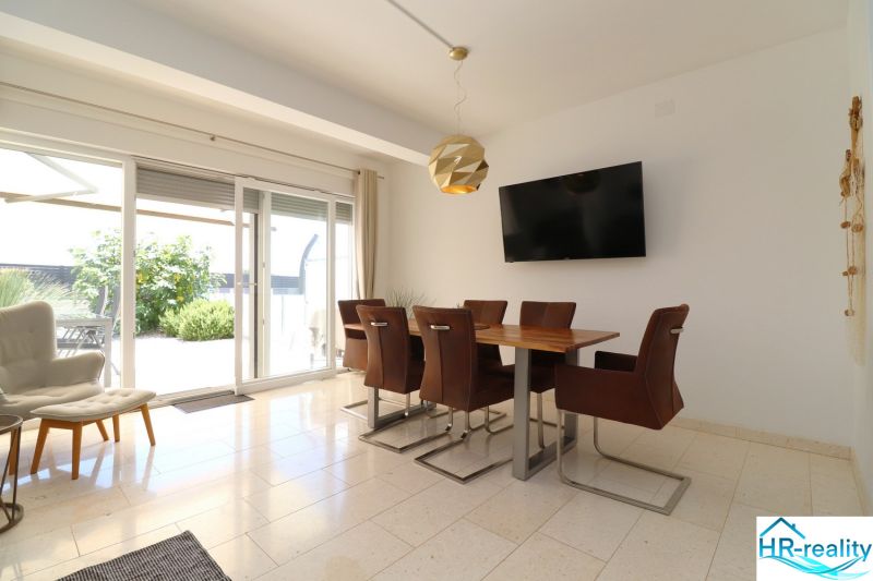 Dining room of a recreational apartment with a television and a large window letting in light.