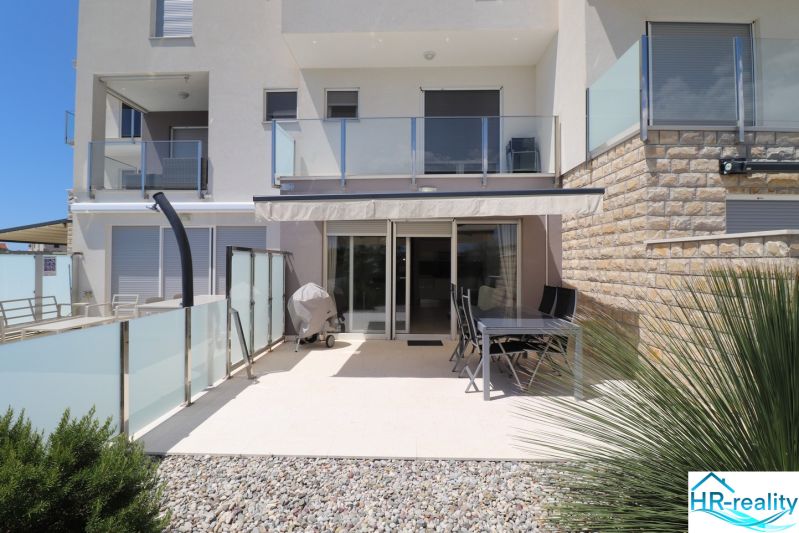 Terrace of a recreational apartment in Tribunj with seating and a grill under an awning.
