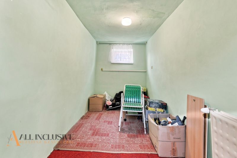 A narrow room in a family house with boxes and a green chair.