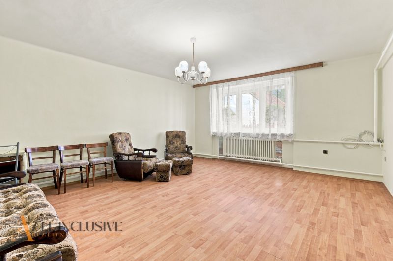 A living room in a family house with armchairs, chairs, and a wooden decor floor.