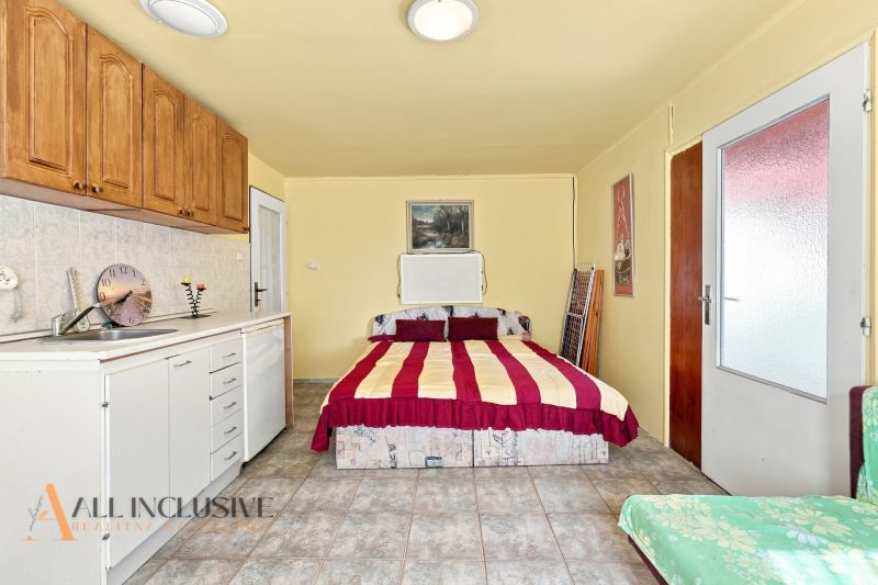 Simple bedroom setup with a kitchenette in a family house, white-brown furniture, bed.