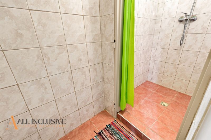 A bathroom in a family house with tiles and a shower in a shade of green.