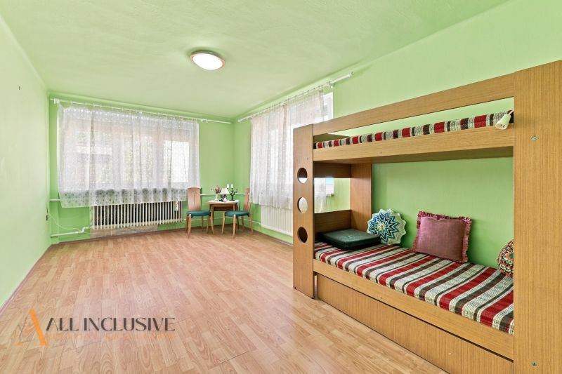 Children's room with a bunk bed, a desk, and a wooden decor floor in a family house.