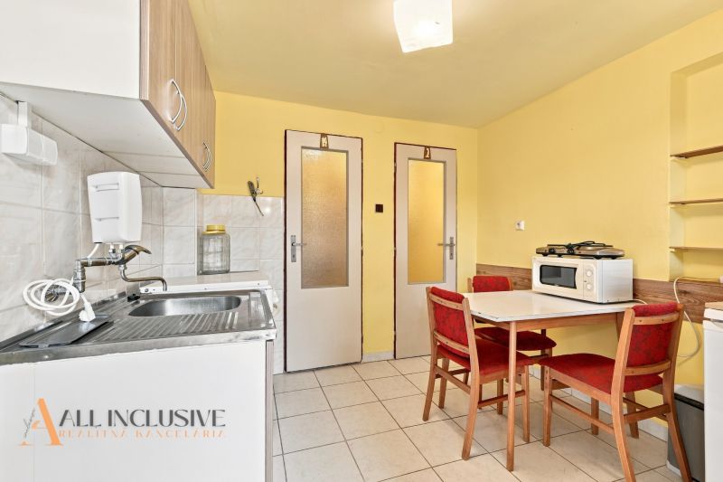 A kitchen in a family house with yellow walls, tiles, and a table with chairs.
