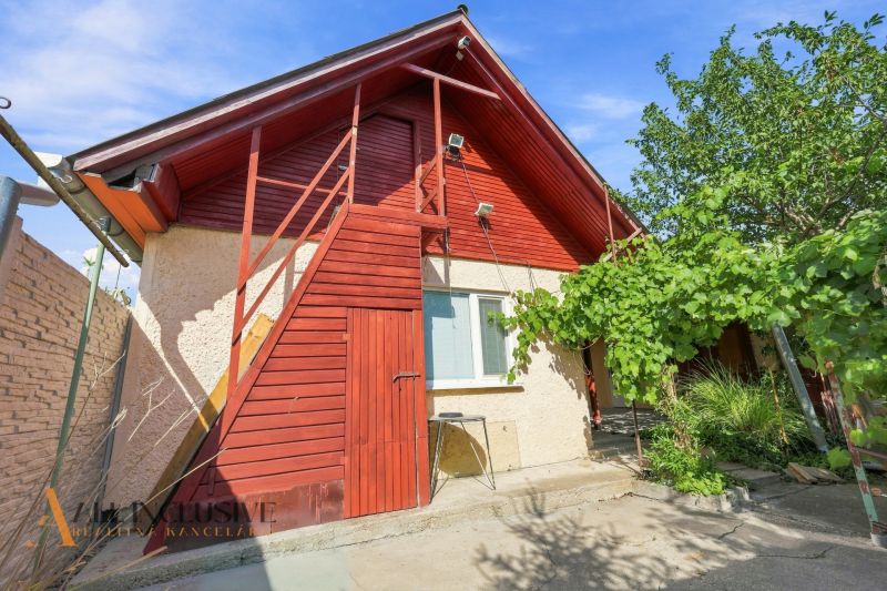 A family house in Veľký Meder with a light facade and red wooden elements.