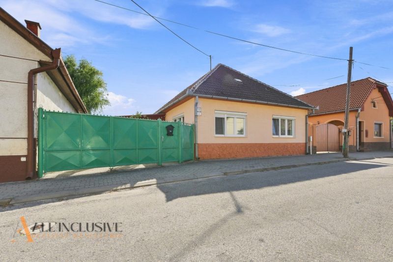 A family house in Veľký Meder with an orange facade and a green gate on the street.