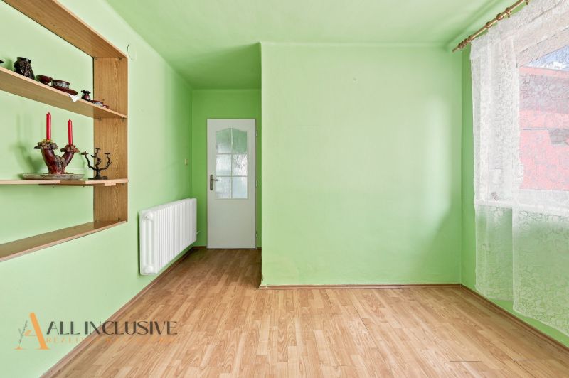 Green room in a family house with a wood-patterned floor and built-in shelves.