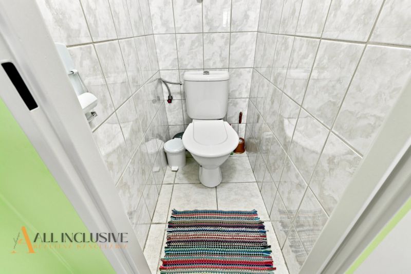 A bathroom with white tiles and a colorful rug in a family house.