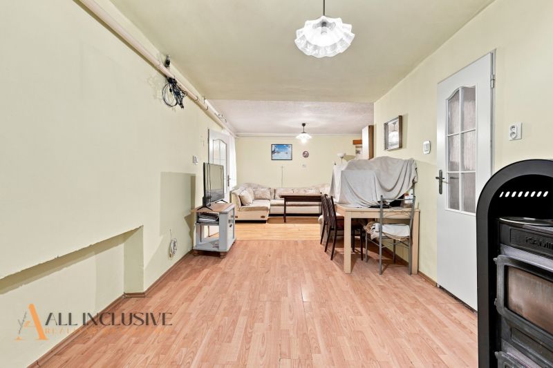 Interior of a family house with a wooden decor floor, a sofa, and a dining table.