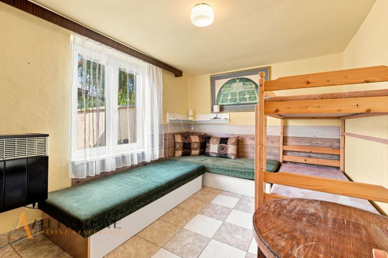 A room in a family house with a bunk bed and a couch, curtains letting in light.