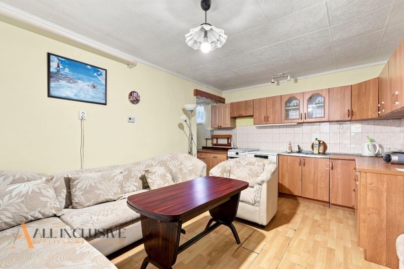 Living room with a kitchenette, sofa, and wooden decor flooring in a family house.