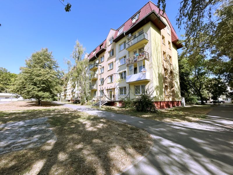 A four-story building with balconies and trees on A. Hlinku Street in Piešťany.