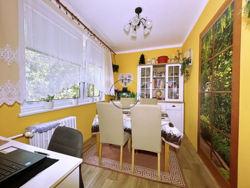 Dining room in a 4-room apartment with yellow walls and wood-patterned flooring.