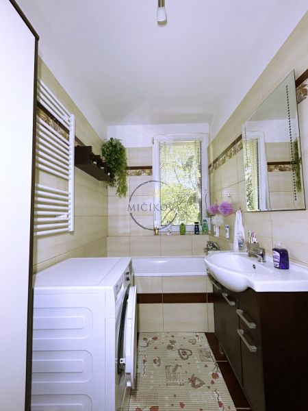A bathroom with a shower, washing machine, and sink in a 4-room apartment.
