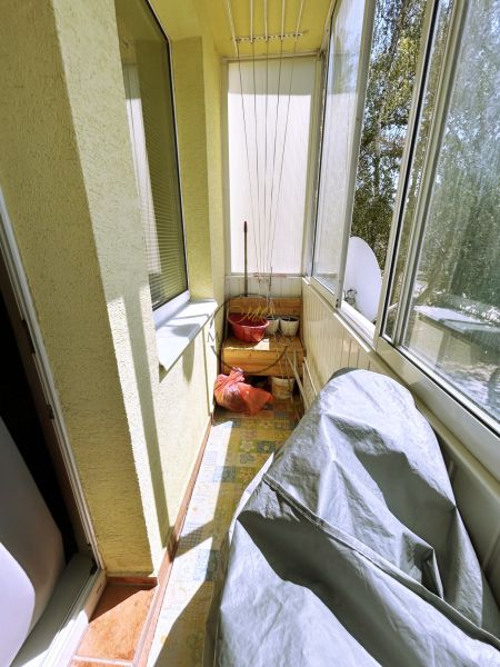 Glazed balcony in a 4-room apartment with storage needs and clothes hangers.