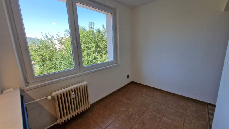 A room in a 3-room apartment with tiles and a large window overlooking greenery.