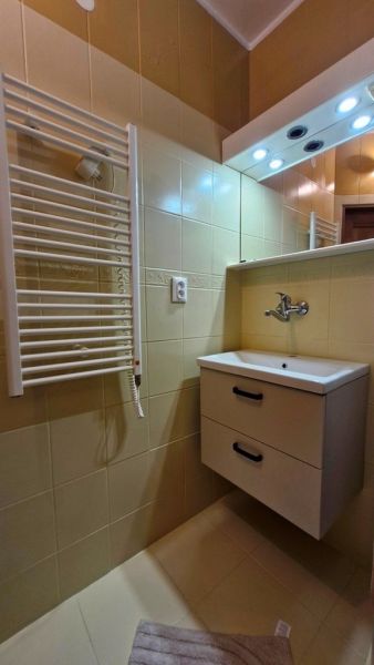 Bathroom with a sink, mirror, and ladder radiator in a 3-room apartment.