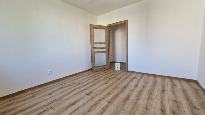 An empty room with a wooden decor floor in a 3-room apartment.