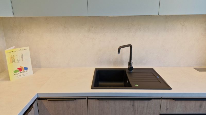 Kitchen unit in a 3-room apartment with cabinets and a black sink.
