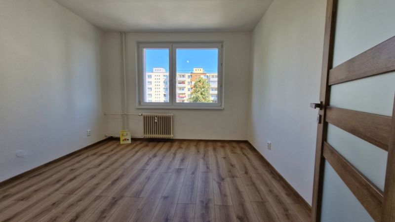 A spacious room with a wooden decor floor in a 3-room apartment.