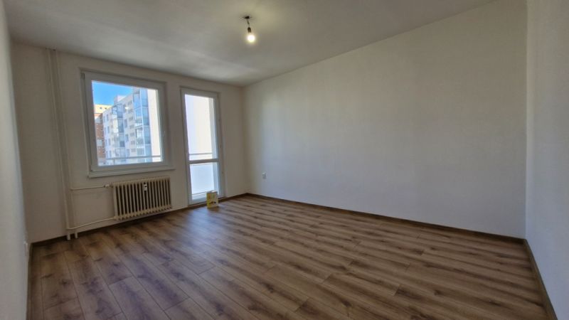 Spacious room in a 3-room apartment with a wood-patterned floor and a large window.