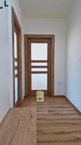 A hallway with a wooden decor floor in a 3-room apartment, wooden doors with frosted glass.