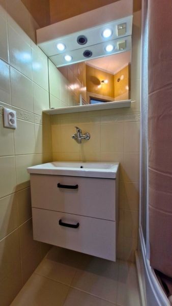 A compact bathroom with a white sink and a mirrored cabinet in a 3-room apartment.