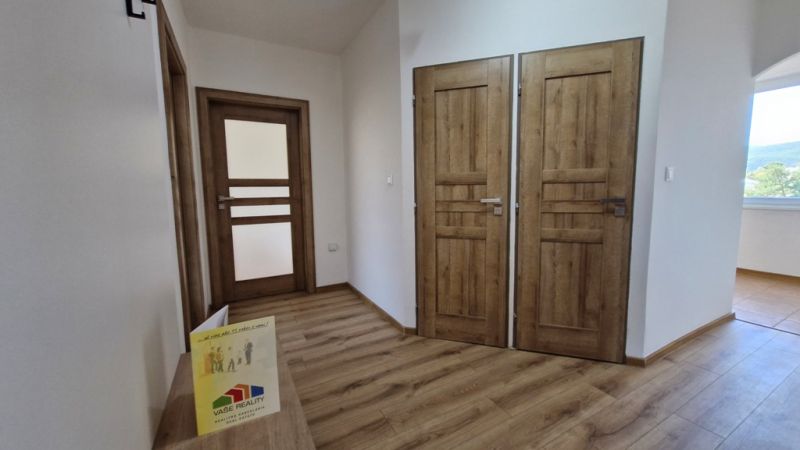 A hallway in a 3-room apartment with a wood-patterned floor and double doors.