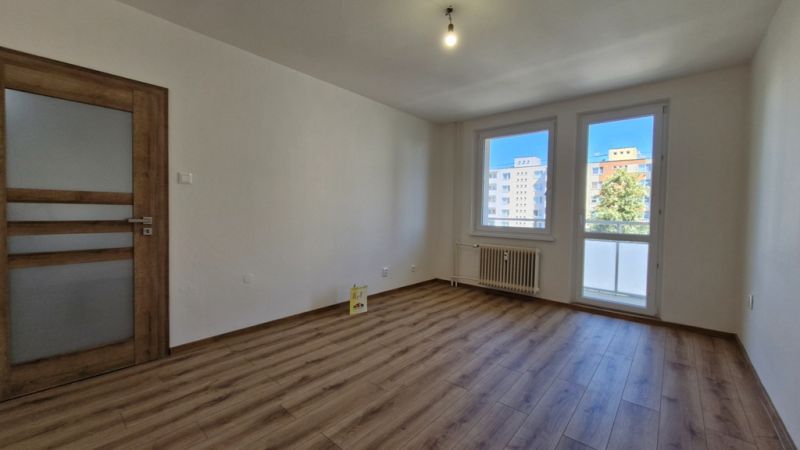 A room in a 3-room apartment with a wooden decor floor and wooden doors.