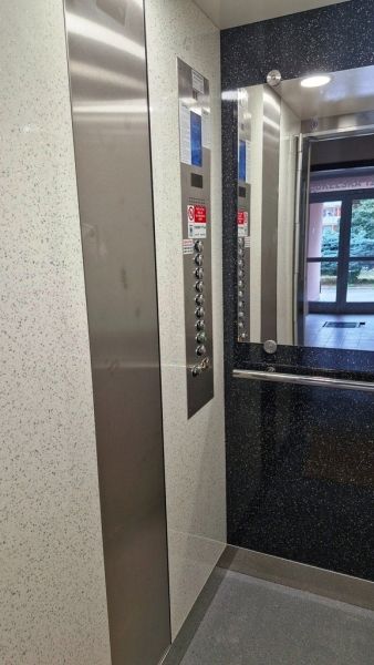 The interior of an elevator with a stainless steel button panel in a 3-room apartment.