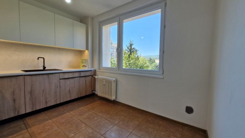 Kitchen in a 3-room apartment, floor with wooden decor, view from the window.