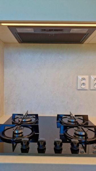 A kitchen unit with a built-in extractor hood and hob in a 3-room apartment.